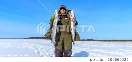 Man Holding a Fish pike in Hands. Winter fishing. Banner, copy space 109666325