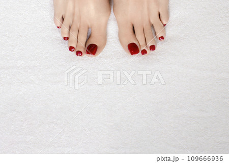 Female toes with glossy red pedicure on white terry towel, copy space. 109666936