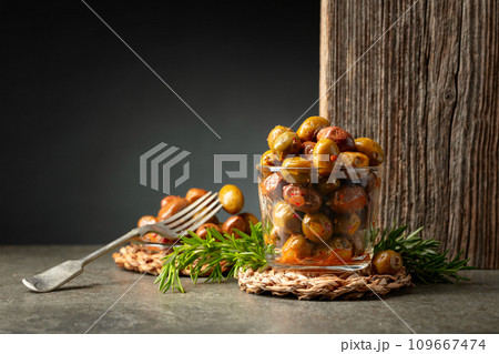 Spicy olives in a glass bowl on a stone table. Spicy olives in a glass bowl on a stone table. 109667474