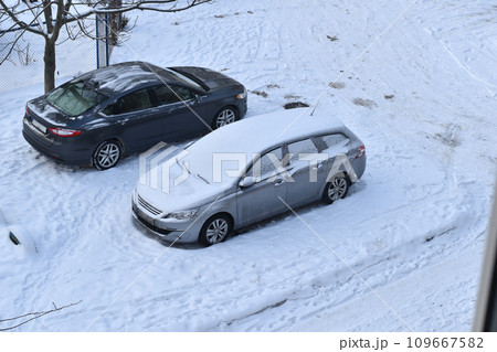 One of the cars in the parking lot is covered with snow, view from above. One of the cars in the parking lot is covered with snow, view from above. 109667582