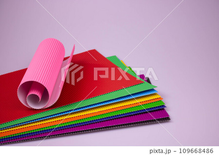 A roll of pink corrugated paper on multicolored leaves of corrugated paper A roll of pink corrugated paper on multicolored leaves of corrugated paper 109668486