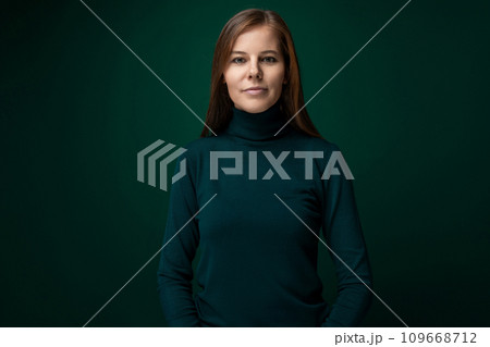 Portrait of a well-groomed young woman with brown eyes on a dark green background Portrait of a well-groomed young woman with brown eyes on a dark green background 109668712