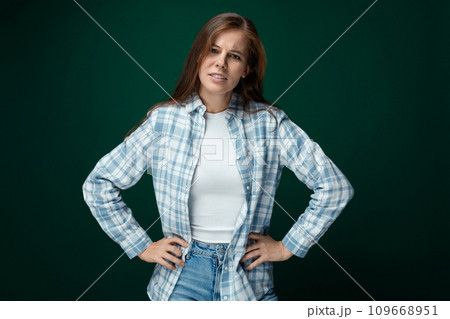 Confident Caucasian young woman stands in a leader's pose on a green studio background 109668951