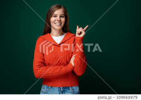Joyful lucky woman wearing a red sweater on a dark green background 109668979