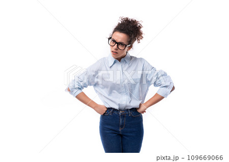 an amazing young brunette curly-haired manager woman is dressed in a loose-fitting light blue shirt 109669066