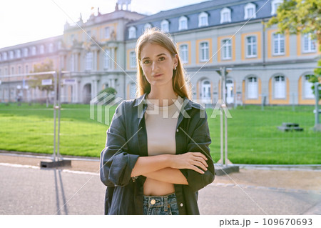 Young girl student posing outdoors, background of educational building 109670693