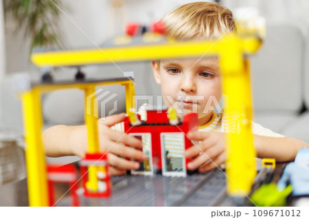 Child boy playing and building with colorful plastic bricks at the table 109671012