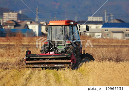田舎の田んぼを耕すトラクター 109673514