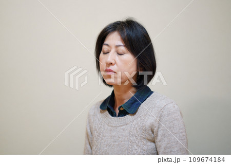 セーターを着て目を閉じる中年女性 109674184