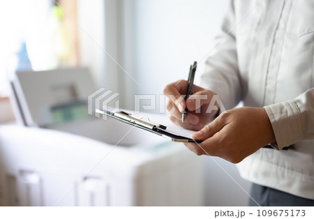 グレーの作業着を着た業者が.洗濯機を点検している グレーの作業着を着た業者が.洗濯機を点検している 109675173