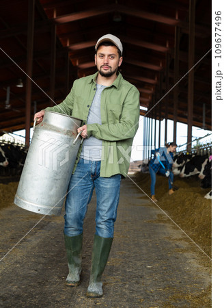 Focused man farmer carrying big milk can Focused man farmer carrying big milk can 109677496
