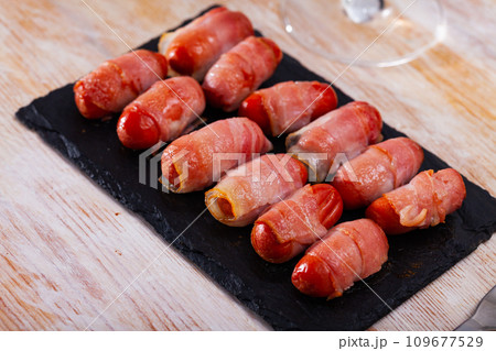 Miniature sausage links wrapped in bacon Miniature sausage links wrapped in bacon 109677529