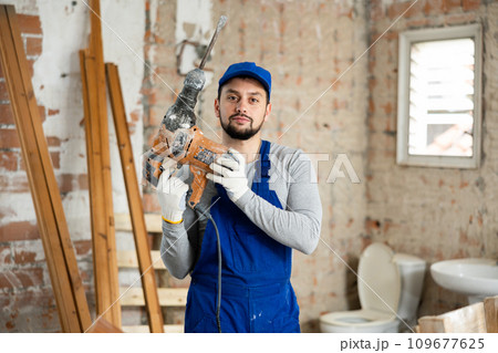 Portrait of a builder holding a hammer drill in his hands 109677625