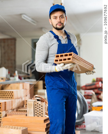 Young contractor stacking bricks on construction site indoors Young contractor stacking bricks on construction site indoors 109677692