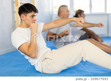 Group of men train abdominal muscles and do punches at the same time during karate or judo training 109677693