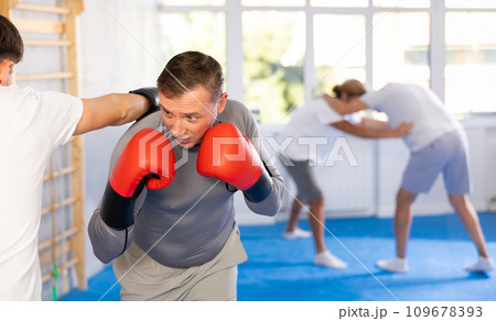 Man and guy in boxing gloves punch deliver blow each other during training sparring session. 109678393