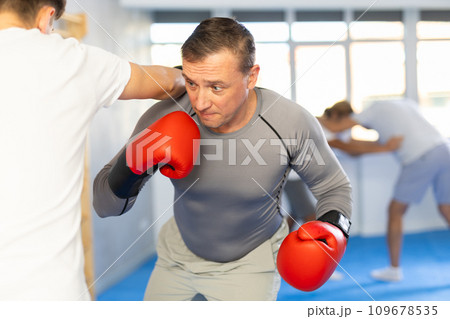 Man and guy in boxing gloves punch deliver blow each other during training sparring session. 109678535