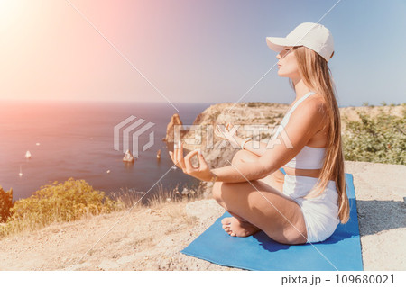Woman sea yoga. Happy woman meditating in yoga pose on the beach, ocean and rock mountains. Motivation and inspirational fit and exercising. Healthy lifestyle outdoors in nature, fitness concept. Woman sea yoga. Happy woman meditating in yoga pose on the beach, ocean and rock mountains. Motivation and inspirational fit and exercising. Healthy lifestyle outdoors in nature, fitness concept. 109680021