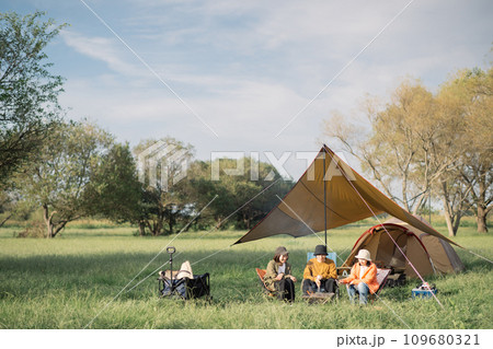 キキャンプを楽しむ若い男女・焚き火・焼きマシュマロをするアウトドアイメージ キキャンプを楽しむ若い男女・焚き火・焼きマシュマロをするアウトドアイメージ 109680321
