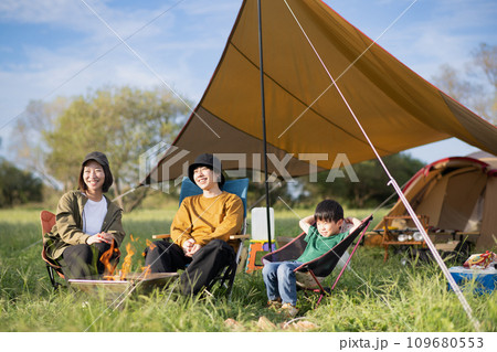キャンプで午後に焚き火をするファミリー 109680553
