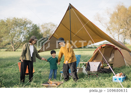 キャンプ場で手を繋いで遊ぶ笑顔のファミリー キャンプ場で手を繋いで遊ぶ笑顔のファミリー 109680631
