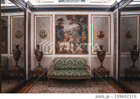 Luxurious and elegant room with green and white couch and ornate paintings on the wall. Opulent decor exudes sophistication. Part of a collection of Venice photos in real Venetian style. 109682319