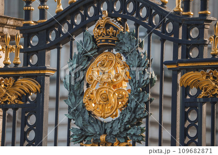 Closeup shot of shield on metal gate. Entrance of Buckingham Palace. Black and golden fence of famous kingdom in London. Closeup shot of shield on metal gate. Entrance of Buckingham Palace. Black and golden fence of famous kingdom in London. 109682871