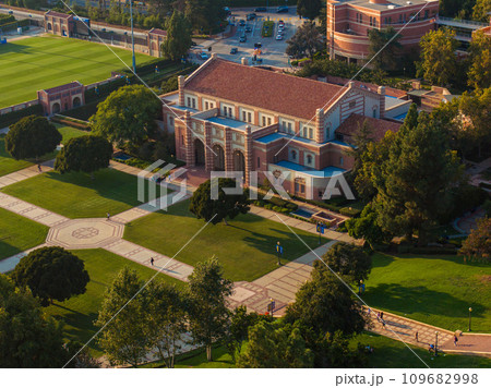 Aerial view of a grand university campus with red-bricked buildings, green lawns, and classical architecture, featuring a sports field, pond, and serene outdoor seating areas. Aerial view of a grand university campus with red-bricked buildings, green lawns, and classical architecture, featuring a sports field, pond, and serene outdoor seating areas. 109682998