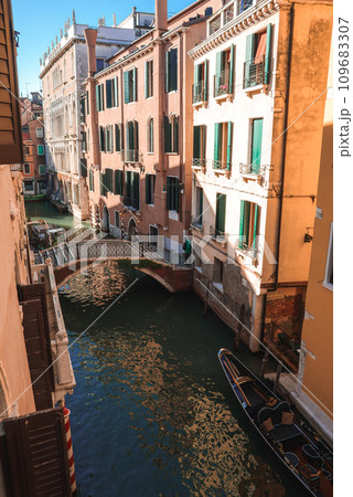 Experience the tranquil beauty of Venice with this serene view of a canal. The peaceful and quiet spot captures the essence of the city's canals during the summer. 109683307