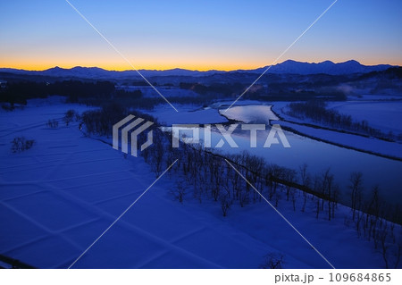 ブルーアワーの空と越後三山を背景にした蛇行する信濃川の風景 109684865