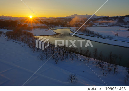 越後三山を望む丘からみた朝焼けの空から昇る太陽と冬の信濃川　Ver2 109684868