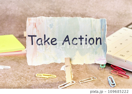 Business concept. Phrase TAKE ACTION written on paper next to scattered paper clips, calculator, adhesive paper 109685222