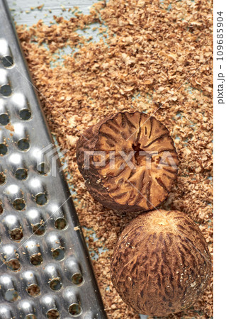 Nutmeg and metal grater against nutmeg powder on blue background 109685904