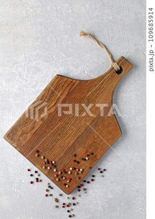 Wooden brown cutting board with colorful peppercorns on a gray concrete table 109685914