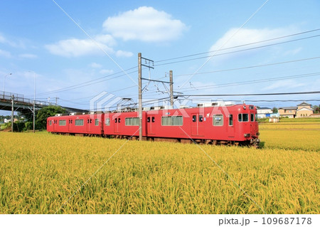 収穫期の田園地帯を走る名鉄三河線電車 109687178