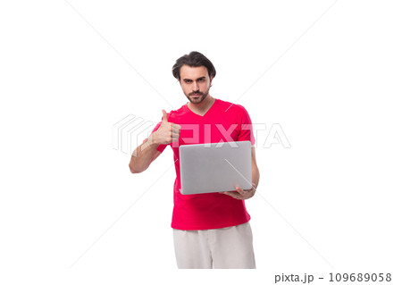 young well-groomed slender brunette man in a red t-shirt holding a laptop 109689058