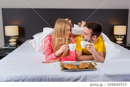 Happy young couple having breakfast tray on bed at home Happy young couple having breakfast tray on bed at home 109689553