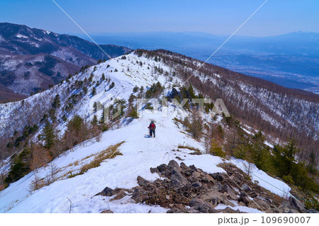 冬の長野県東御市の小烏帽子岳の山頂から下る登山者と南東側の眺望(小諸市,三方ヶ峰など) 冬の長野県東御市の小烏帽子岳の山頂から下る登山者と南東側の眺望(小諸市,三方ヶ峰など) 109690007