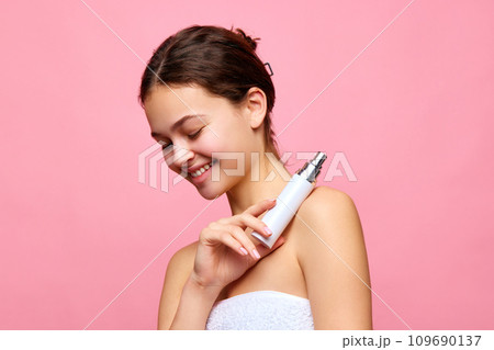 Pretty, beautiful young girl holding moisturizing, nourishing face cream against pink background Pretty, beautiful young girl holding moisturizing, nourishing face cream against pink background 109690137