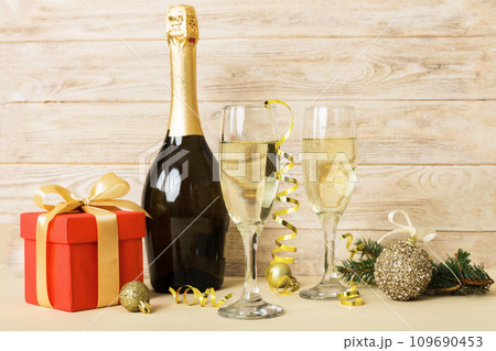 Champagne bottle with confetti, glasses and christmas decor on colored holiday background. Flat lay New Year decorations 109690453