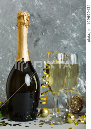 Champagne bottle with confetti, glasses and christmas decor on colored holiday background. Flat lay New Year decorations 109690454