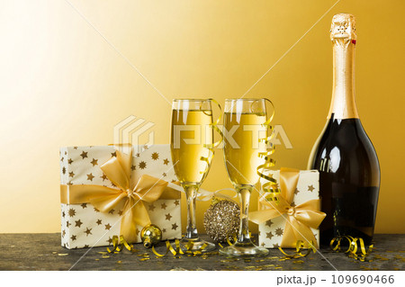 Champagne bottle with confetti, glasses and christmas decor on colored holiday background. Flat lay New Year decorations Champagne bottle with confetti, glasses and christmas decor on colored holiday background. Flat lay New Year decorations 109690466