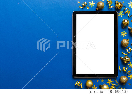 Christmas online shopping from home tablet pc with blank white display top view. Tablet with copy space on colored background with Christmas decorations balls,. Winter holidays sales background Christmas online shopping from home tablet pc with blank white display top view. Tablet with copy space on colored background with Christmas decorations balls,. Winter holidays sales background 109690535