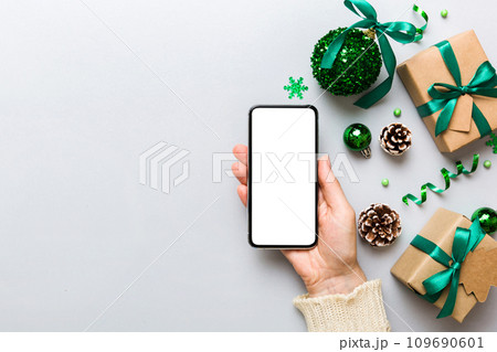 christmas mockup with space for text. christmas advertising, app template. hand holding phone with empty screen on table background. Happy New Year and Xmas Flat lay christmas mockup with space for text. christmas advertising, app template. hand holding phone with empty screen on table background. Happy New Year and Xmas Flat lay 109690601