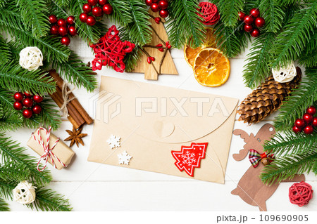 Top view of fir tree branches, envelope and festive decorative toys on wooden background. New Year time concept Top view of fir tree branches, envelope and festive decorative toys on wooden background. New Year time concept 109690905
