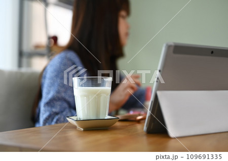 A glass and bottle of milk on wooden table with child girl doing homework on background 109691335