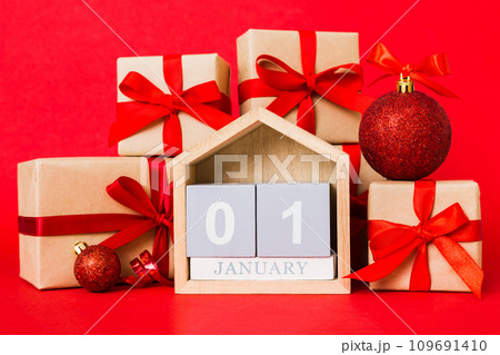 1 january. Christmas composition on colored background with a wooden calendar, with a gift box, toys, bauble copy space 109691410