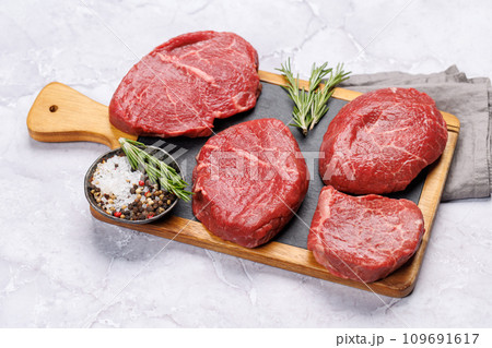 Raw beef fillet steaks on a cutting board, fresh and uncooked Raw beef fillet steaks on a cutting board, fresh and uncooked 109691617