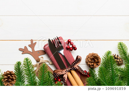 Top view of flatware tied up with ribbon on napkin on wooden background. Christmas decorations and reindeer with empty space for your design. New Year holiday concept 109691859