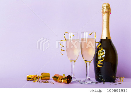 Champagne bottle with confetti, glasses and christmas decor on colored holiday background. Flat lay New Year decorations 109691953